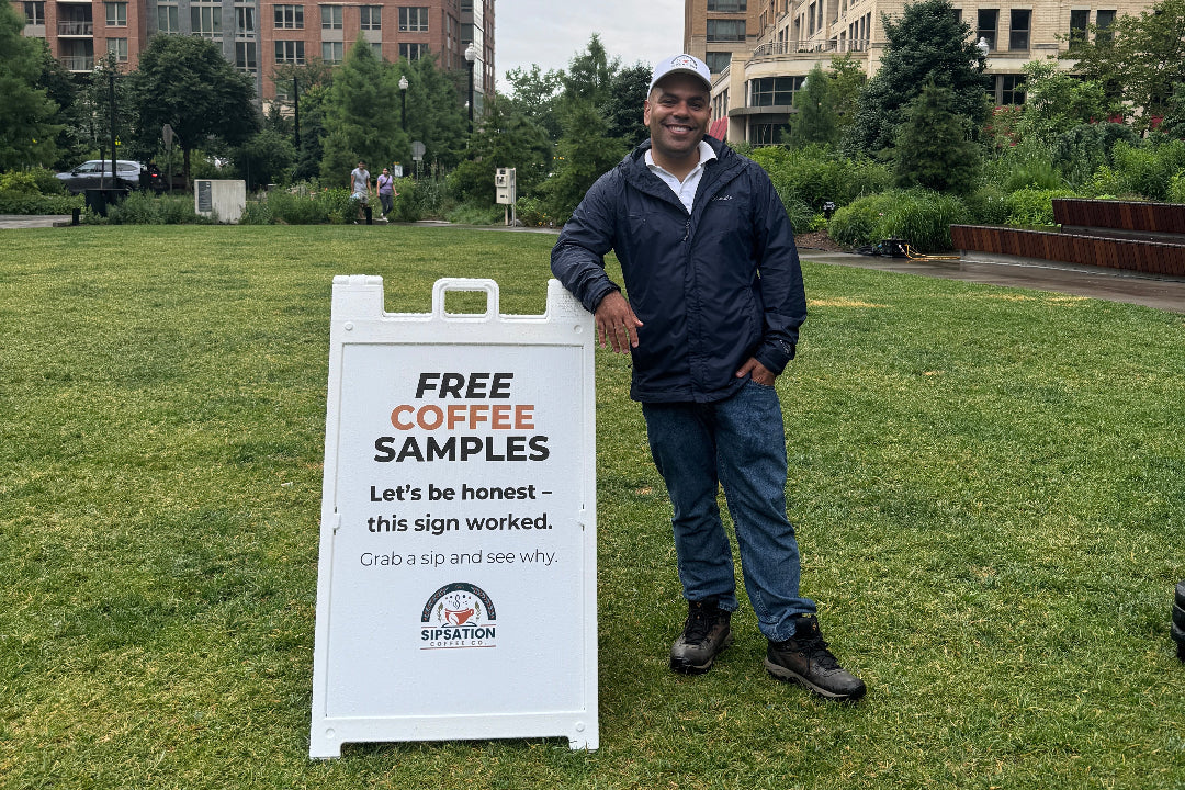 A photo of the founder, Andrew, at the MetPark farmers market in Arlington, VA next to a SipSation sign.