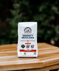 A bag of Serenity Mexicana coffee placed on a wooden table with a blurred background.